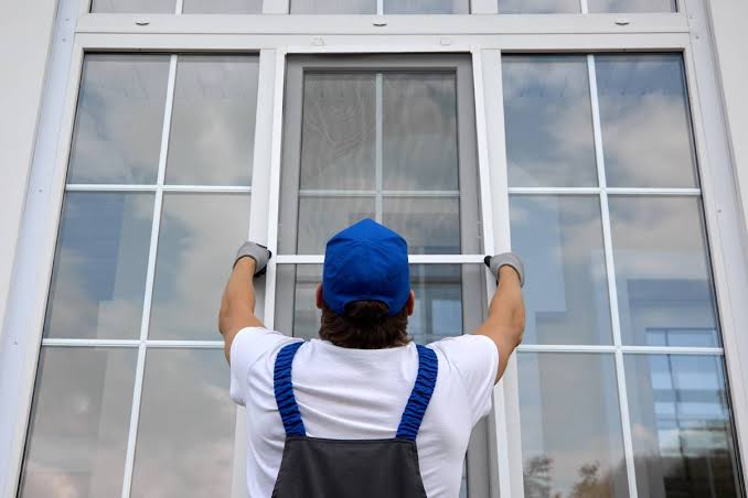 Tecnico installatore monta nuove finestre in PVC bianche con vetro basso emissivo: posa professionale a regola d'arte con tre livelli di sigillatura