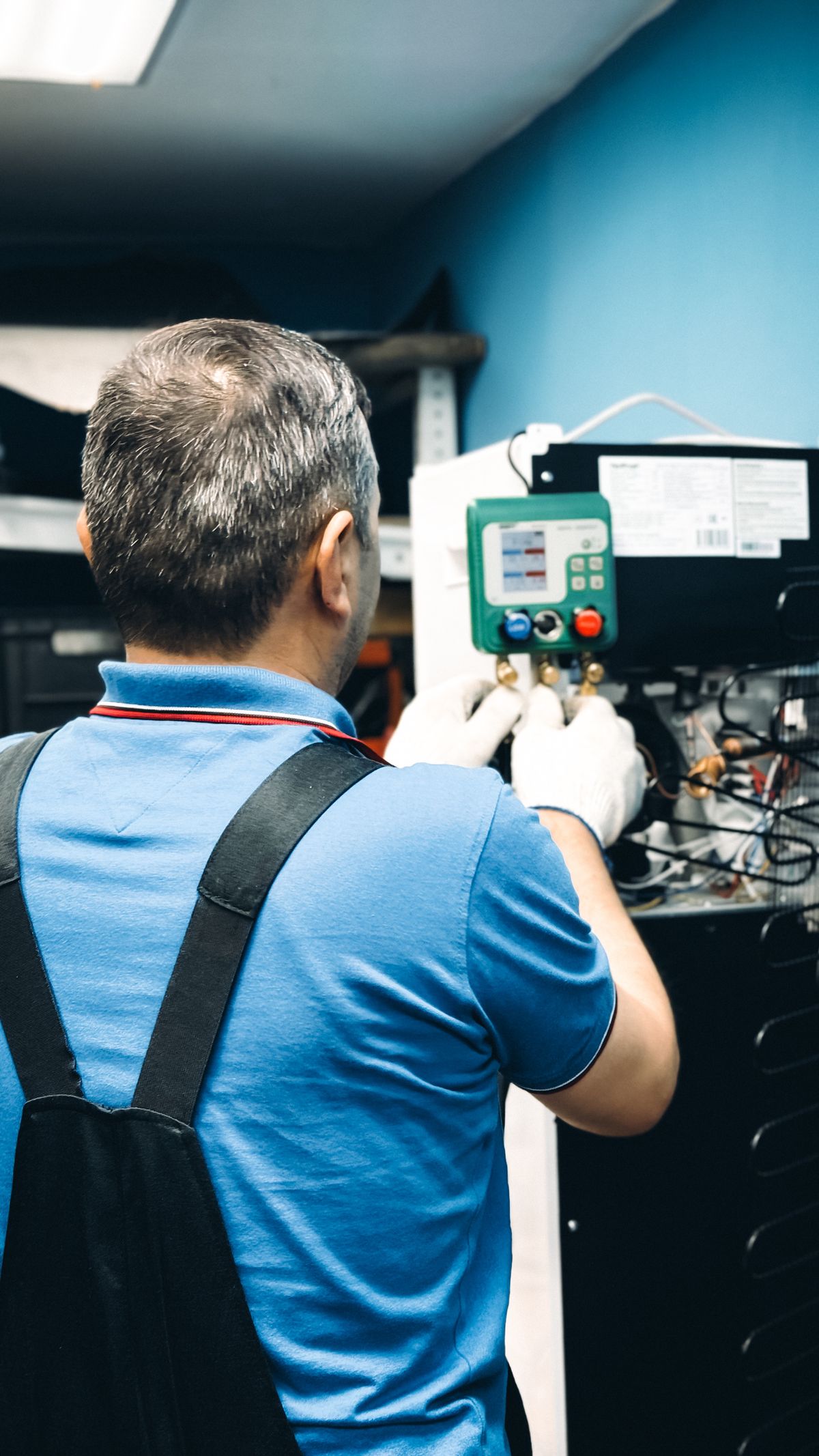 Tecnico installatore termoidraulico al lavoro su impianto pompa di calore con manometri e refrigerante R-32